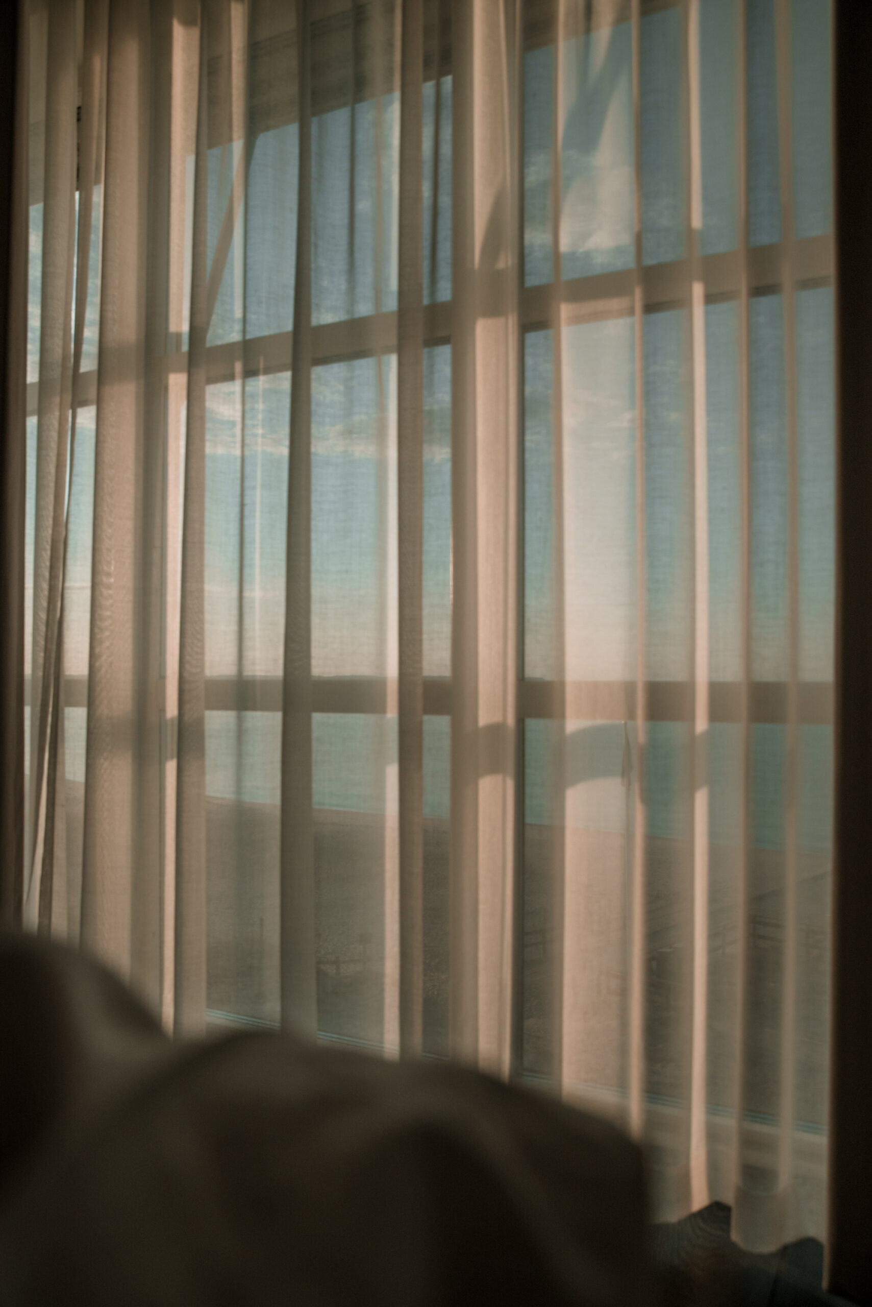 Mjuk morgonljus genom gardiner med utsikt över havet på Ystad Saltsjöbad.