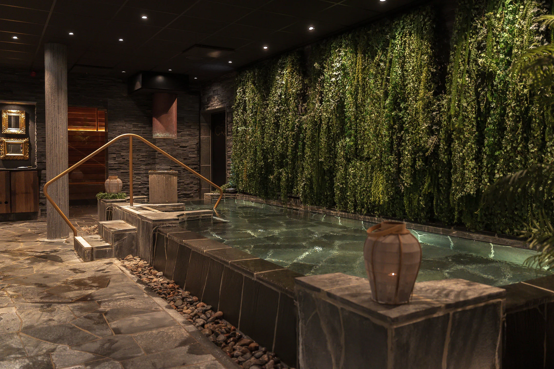 Inomhuspool med grön växtvägg, varm belysning och exklusiv spa-miljö på Ystad Saltsjöbad.