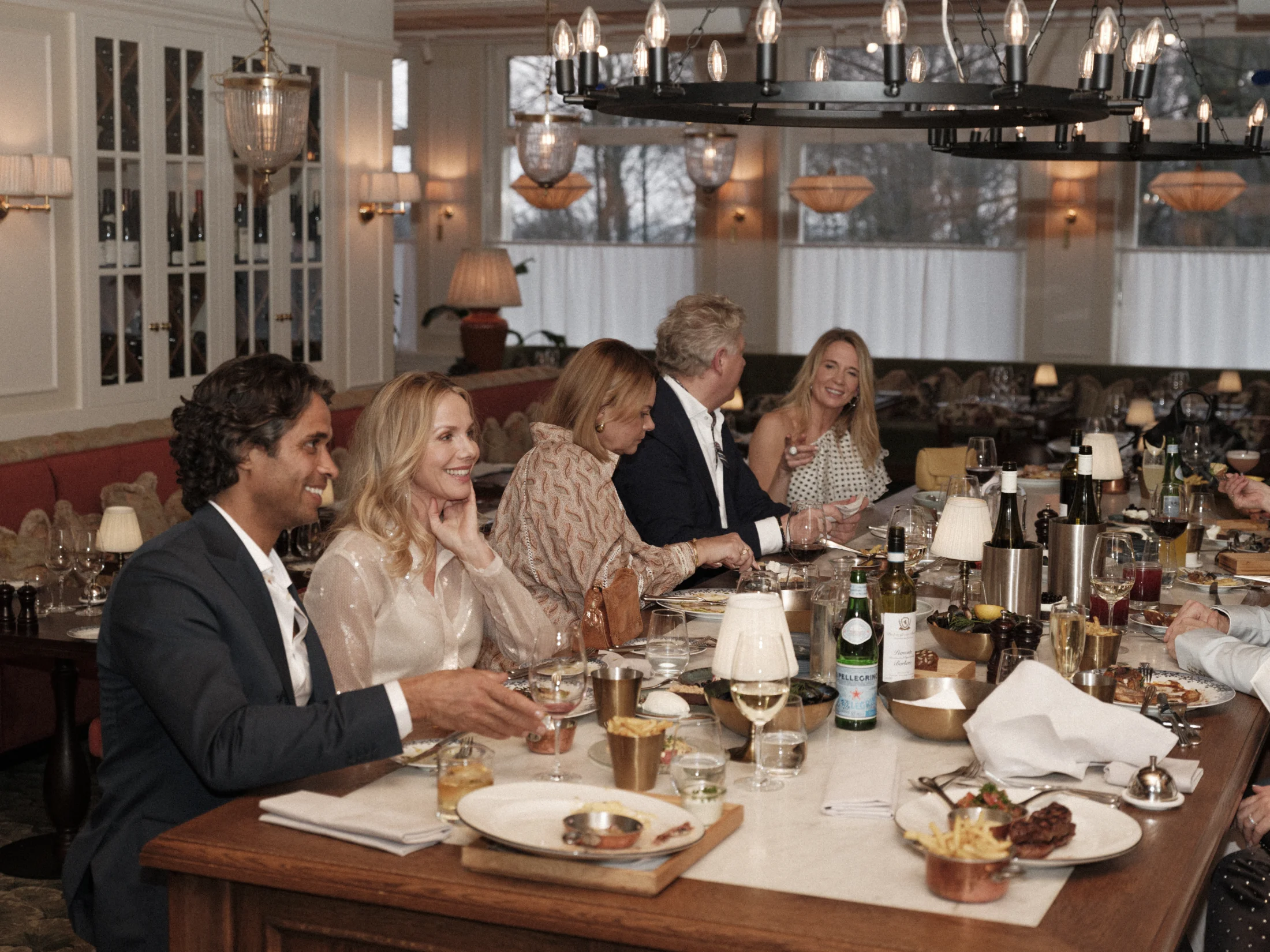 Middagssällskap som njuter av en lång middag i elegant restaurangmiljö på Ystad Saltsjöbad.